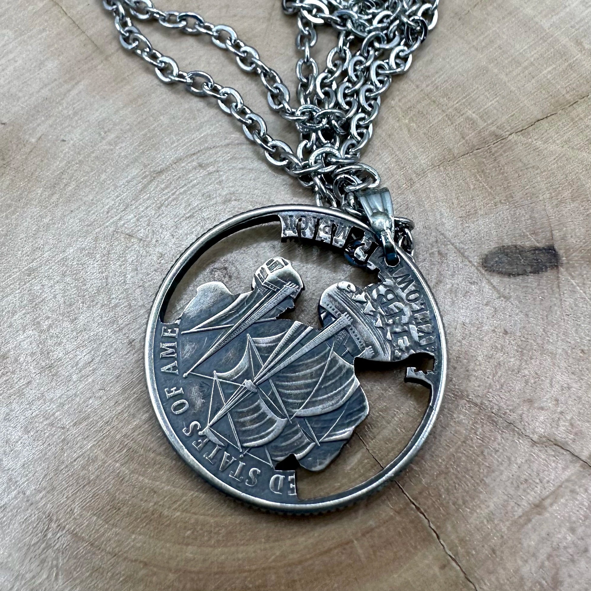 U.S. 2026 "Pilgrim" Quarter Hand Cut Coin Necklace back with a stainless chain on a wood round. -Mountainstruck Coin Jewelry