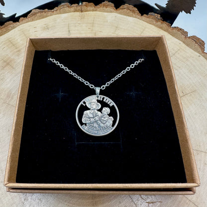 U.S. 2026 "Pilgrim" Quarter Hand Cut Coin Necklace with a stainless chain on a black velvet background in a brown kraft box on a wood round. -Mountainstruck Coin Jewelry