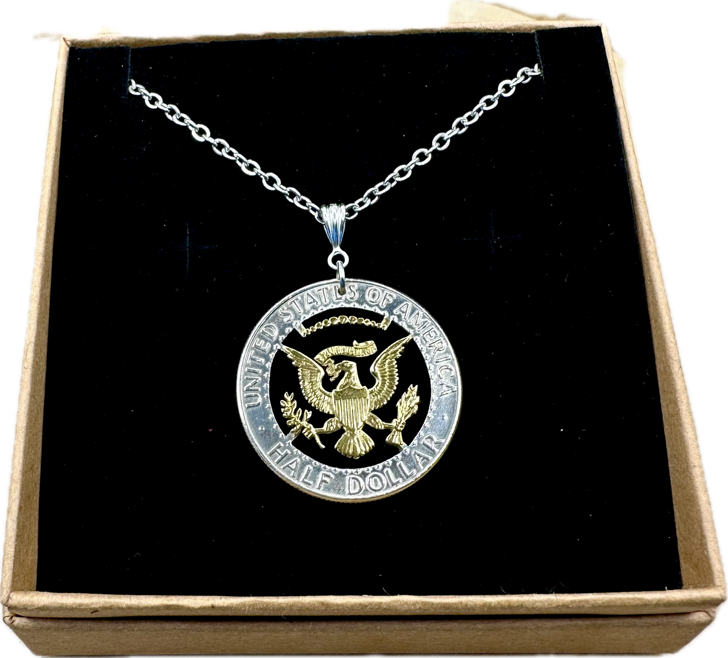 U.S. JFK Eagle Half Dollar Hand Cut Silver Coin Necklace with 24k gold plated Eagle in a brown kraft box on a black velvet background. - Mountainstruck Coin Jewelry