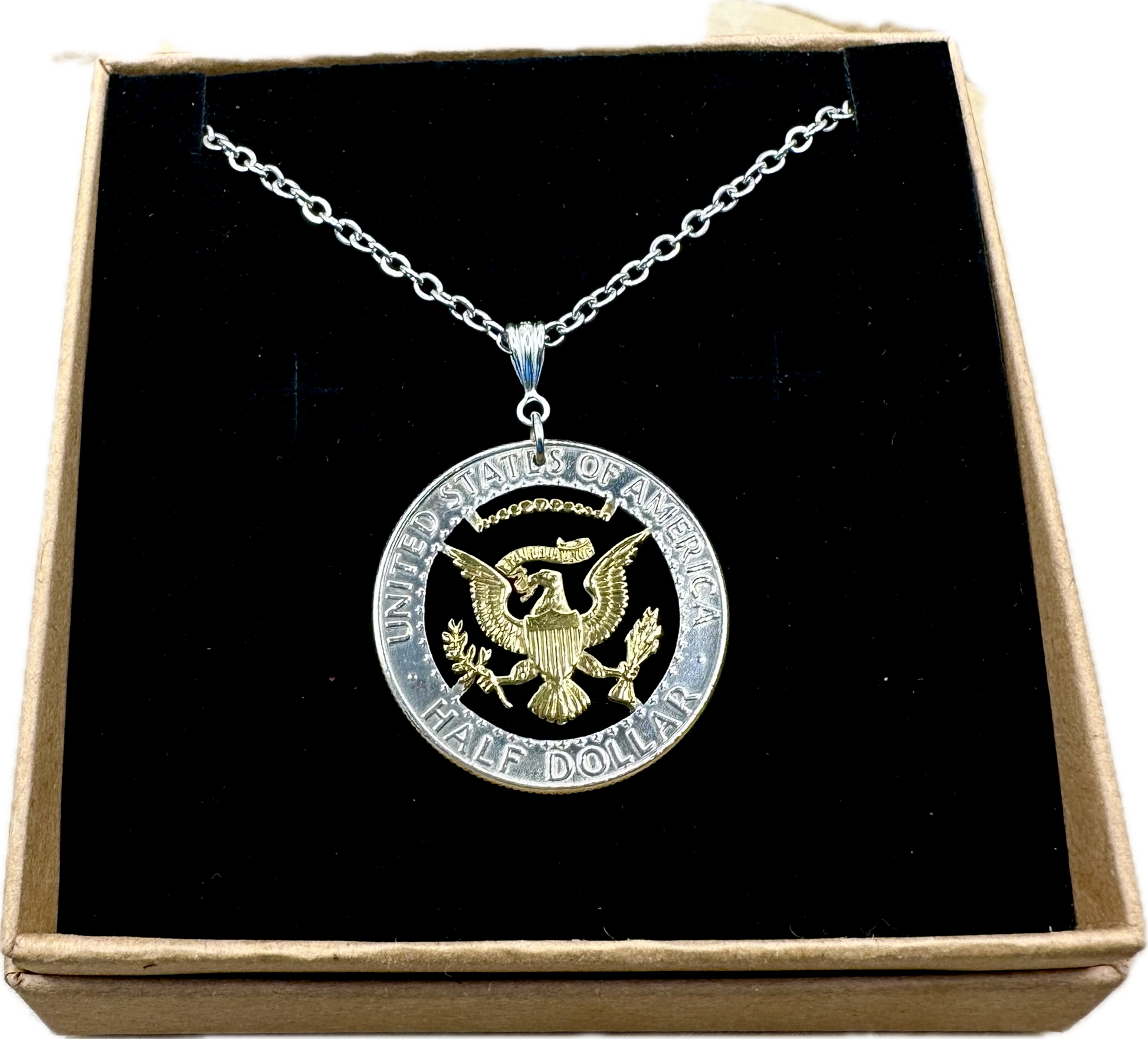 U.S. JFK Eagle Half Dollar Hand Cut Silver Coin Necklace with 24k gold plated Eagle in a brown kraft box on a black velvet background. - Mountainstruck Coin Jewelry