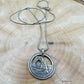 U.S. Arches National Park Hand Cut Coin Necklace with snake chain on a light wood round. - Mountainstruck Coin Jewelry