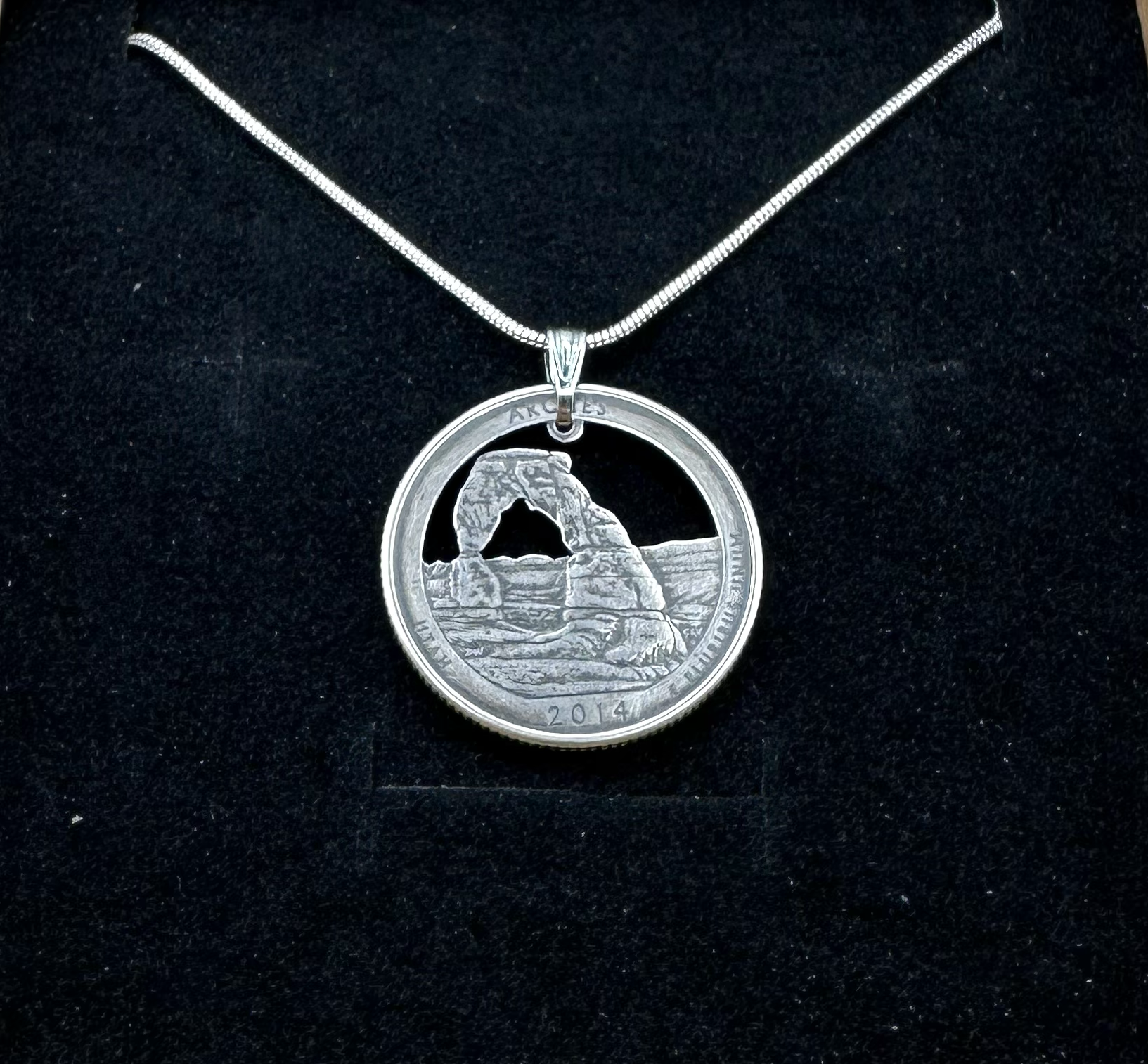 U.S. Arches National Park Hand Cut Coin Necklace with snake chain on a black velvet background. - Mountainstruck Coin Jewelry