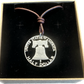 U.S. Cracked Liberty Bell Half Dollar Hand Cut Coin Necklace with a leather cord in a brown kraft box on a black velvet background. - Mountainstruck Coin Jewelry