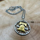 U.S. Cracked Liberty Bell Half Dollar Hand Cut Coin Necklace 24k Gold Plated Bell with a stainless chain on a light wood background. - Mountainstruck Coin Jewelry