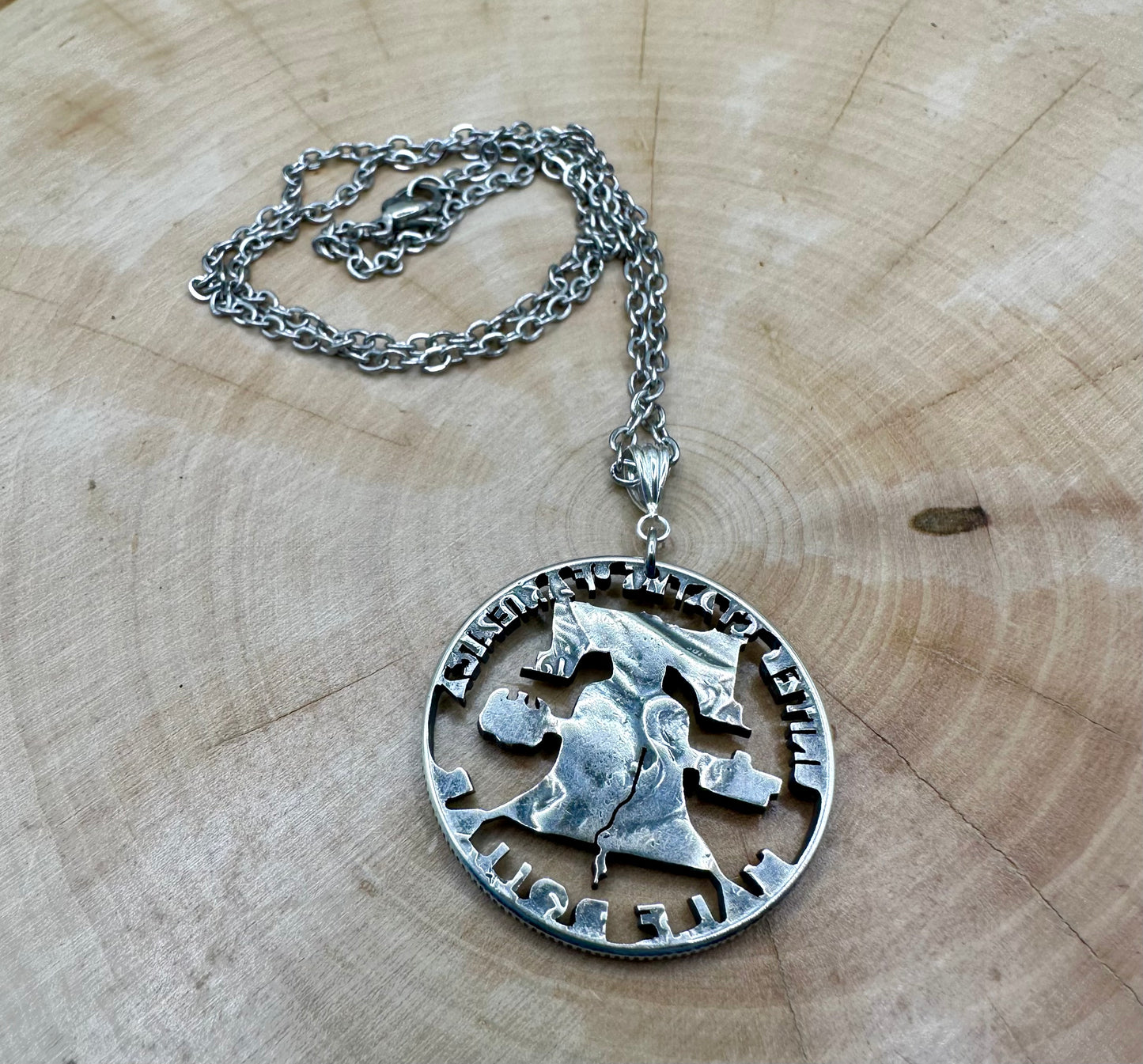 Cracked Liberty Bell U.S. Half Dollar Hand Cut Coin Necklace with stainless chain on a wood background. - Mountainstruck Coin Jewelry