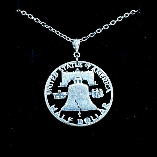 U.S. Cracked Liberty Bell Half Dollar Hand Cut Coin Necklace with a stainless chain on a black velvet background. - Mountainstruck Coin Jewelry