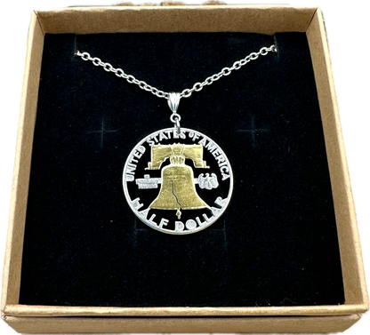 U.S. Cracked Liberty Bell Half Dollar Hand Cut Coin Necklace 24k Gold Plated Bell with a stainless chain in a brown kraft box on a black velvet background. - Mountainstruck Coin Jewelry