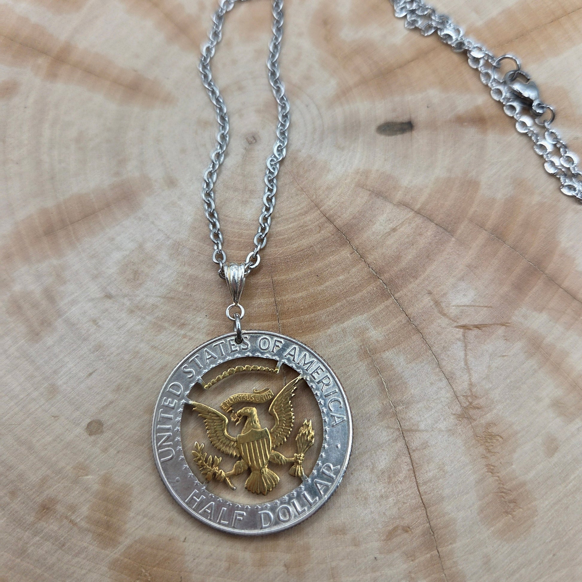 U.S. Eagle Half Dollar Hand Cut Silver Coin Necklace with 24k gold plated eagle on a wood background. - Mountainstruck Coin Jewelry