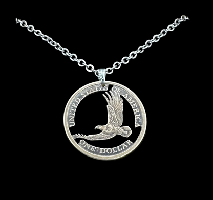U.S. Flying Eagle Sacajawea One Dollar Hand Cut Coin Necklace with snake chain in a brown kraft box on a black velvet background. - Mountainstruck Coin Jewelry