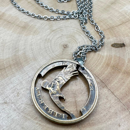 U.S. Flying Eagle Sacajawea One Dollar Hand Cut Coin Necklace with snake chain back on a light wood round. - Mountainstruck Coin Jewelry