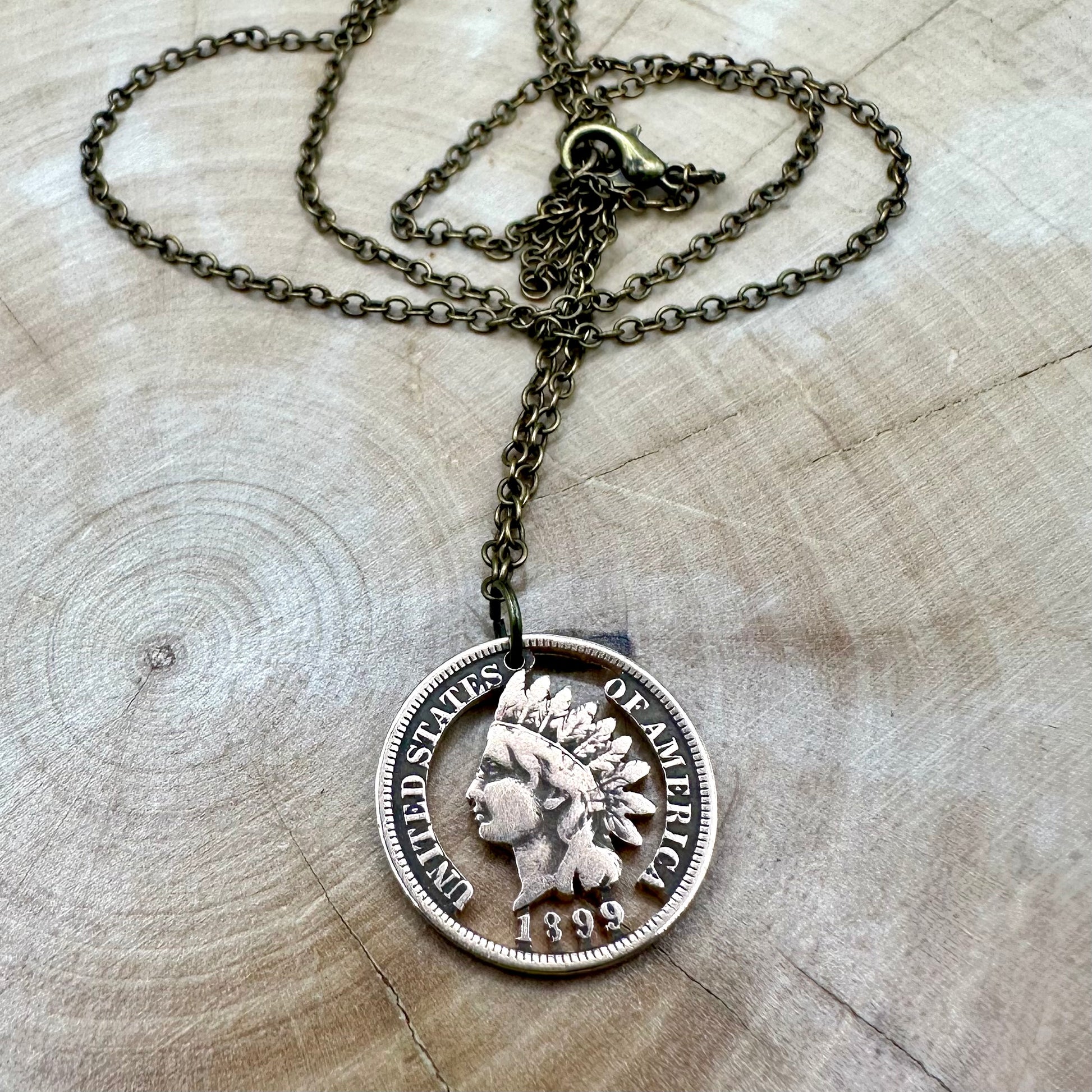 U.S. Indian Head Penny Hand Cut Coin Necklace with bronze chain on light a wood background. - Mountainstruck Coin Jewelry