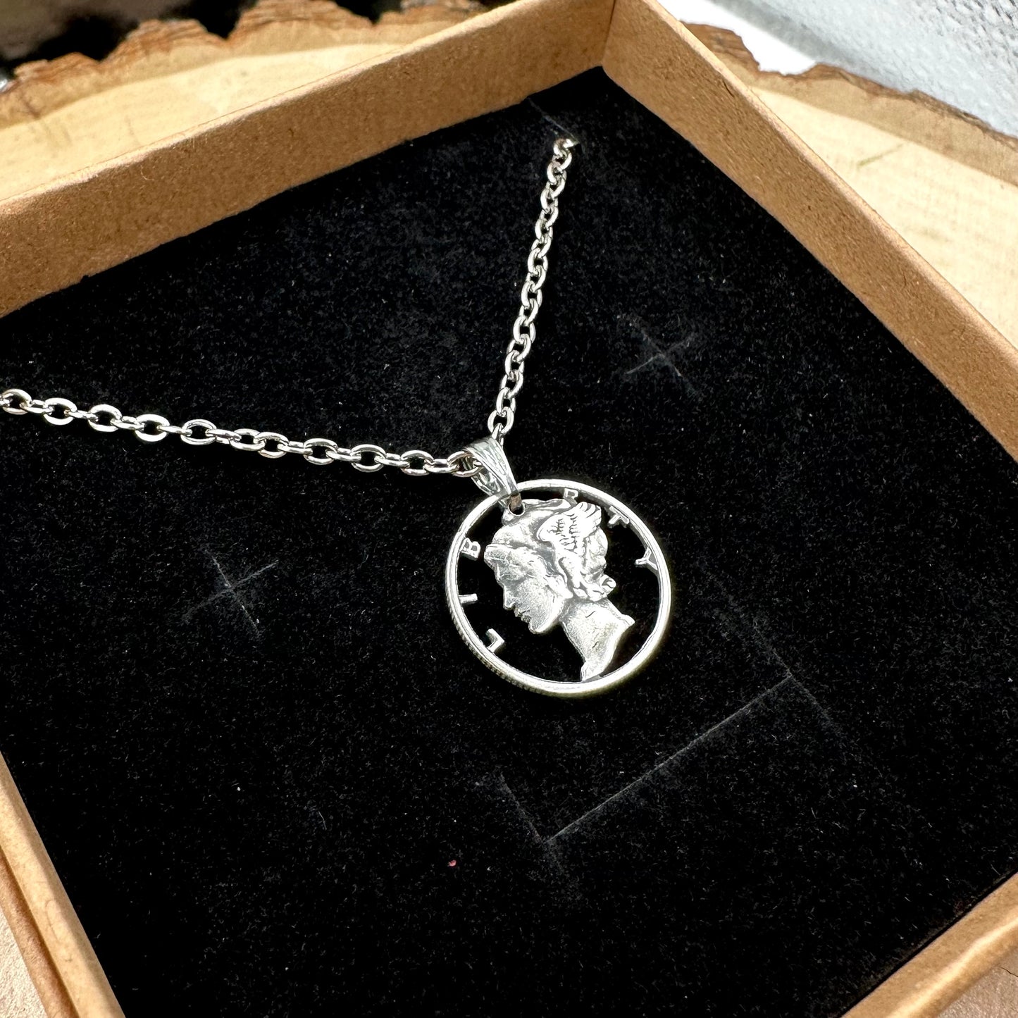 U.S. Mercury Dime Silver Hand Cut Coin Necklace (stainless chain) in a brown kraft box on a black velvet background on top a wood round. - Mountainstruck Coin Jewelry