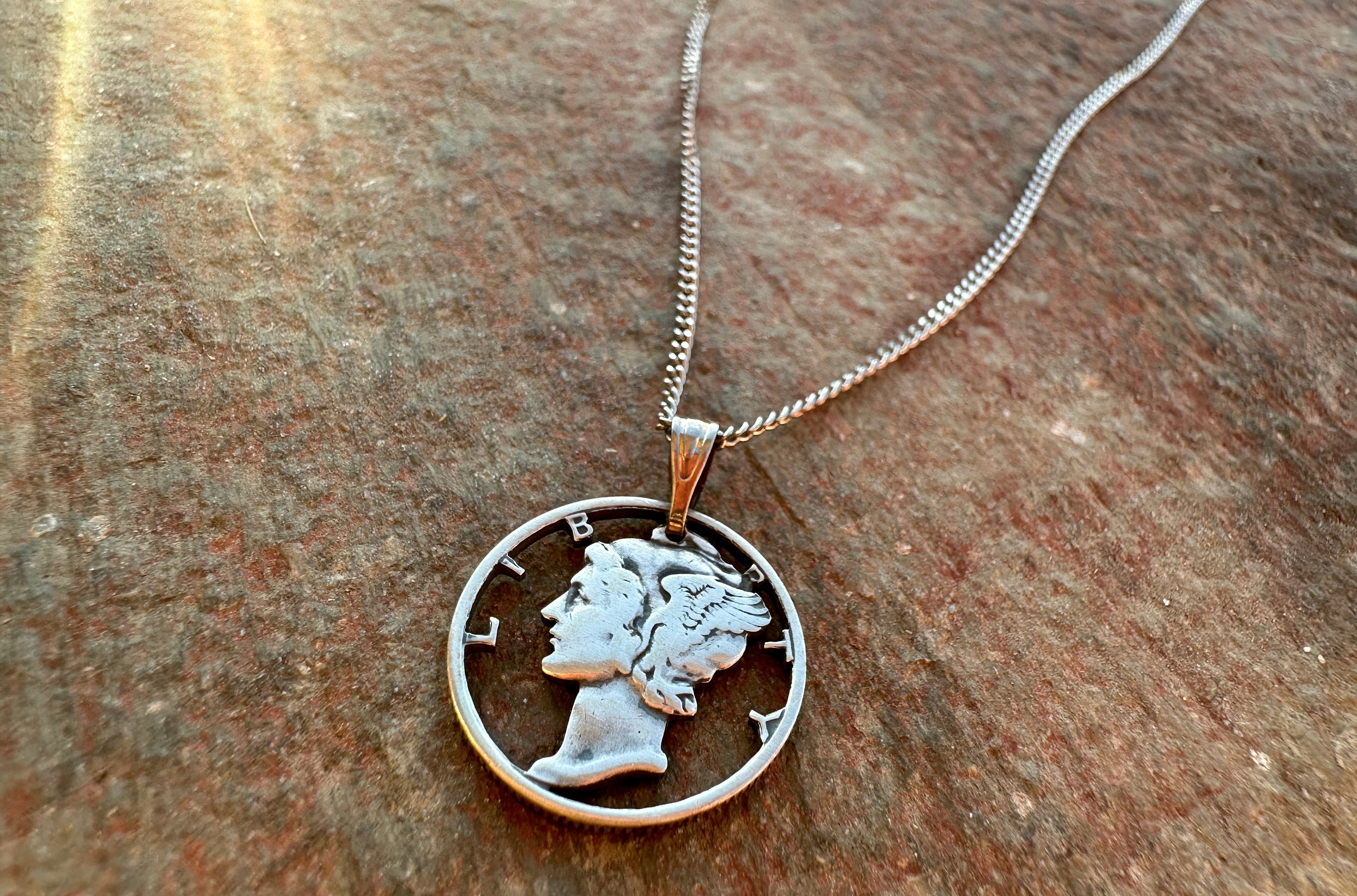 U.S. Mercury dime Hand Cut Silver coin Necklace on a red flagstone rock background. - Mountainstruck Coin Jewelry