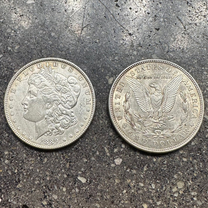 U.S. Morgan Silver Dollar Coin on concrete background. Front side of coin on left of picture and back side of coin on the right. - Mountainstruck Coin Jewelry