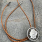 U.S. Morgan Hand Cut Silver Dollar Coin Bolo Tie (front) on a grey rock surface. - Mountainstruck Coin Jewelry