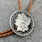 U.S. Morgan Hand Cut Silver Dollar Coin Bolo Tie (front) on a grey rock surface. - Mountainstruck Coin Jewelry