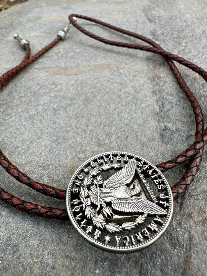 U.S. Morgan Hand Cut Silver Dollar Coin Bolo Tie (reverse) on a grey rock surface. - Mountainstruck Coin Jewelry