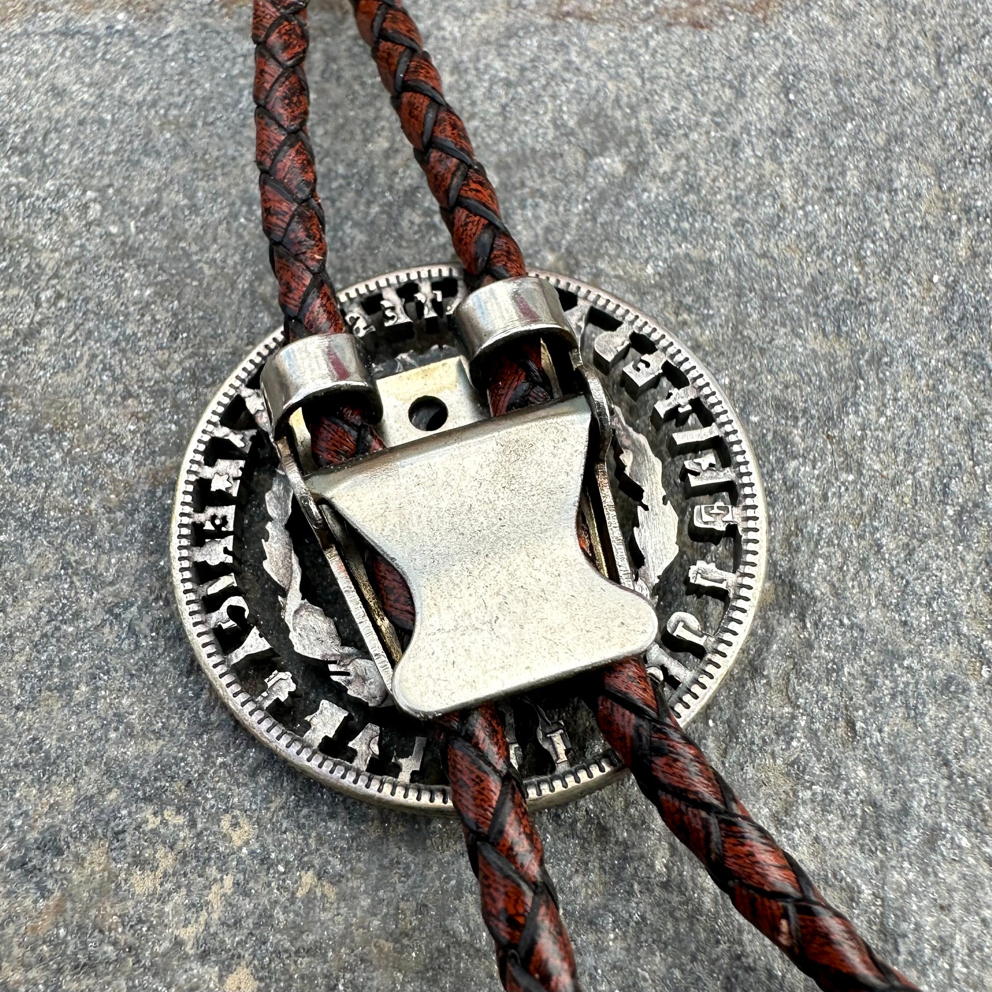 U.S. Morgan Hand Cut Silver Dollar Coin Bolo Tie (reverse) back on a grey rock surface. - Mountainstruck Coin Jewelry
