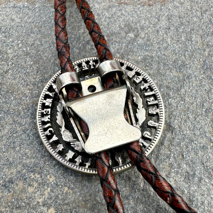 U.S. Morgan Hand Cut Silver Dollar Coin Bolo Tie (reverse) back on a grey rock surface. - Mountainstruck Coin Jewelry
