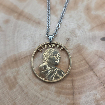 U.S. Sacagawea 1 Dollar Hand Cut Coin Necklace with stainless chain on a wood background. - Mountainstruck Coin Jewelry