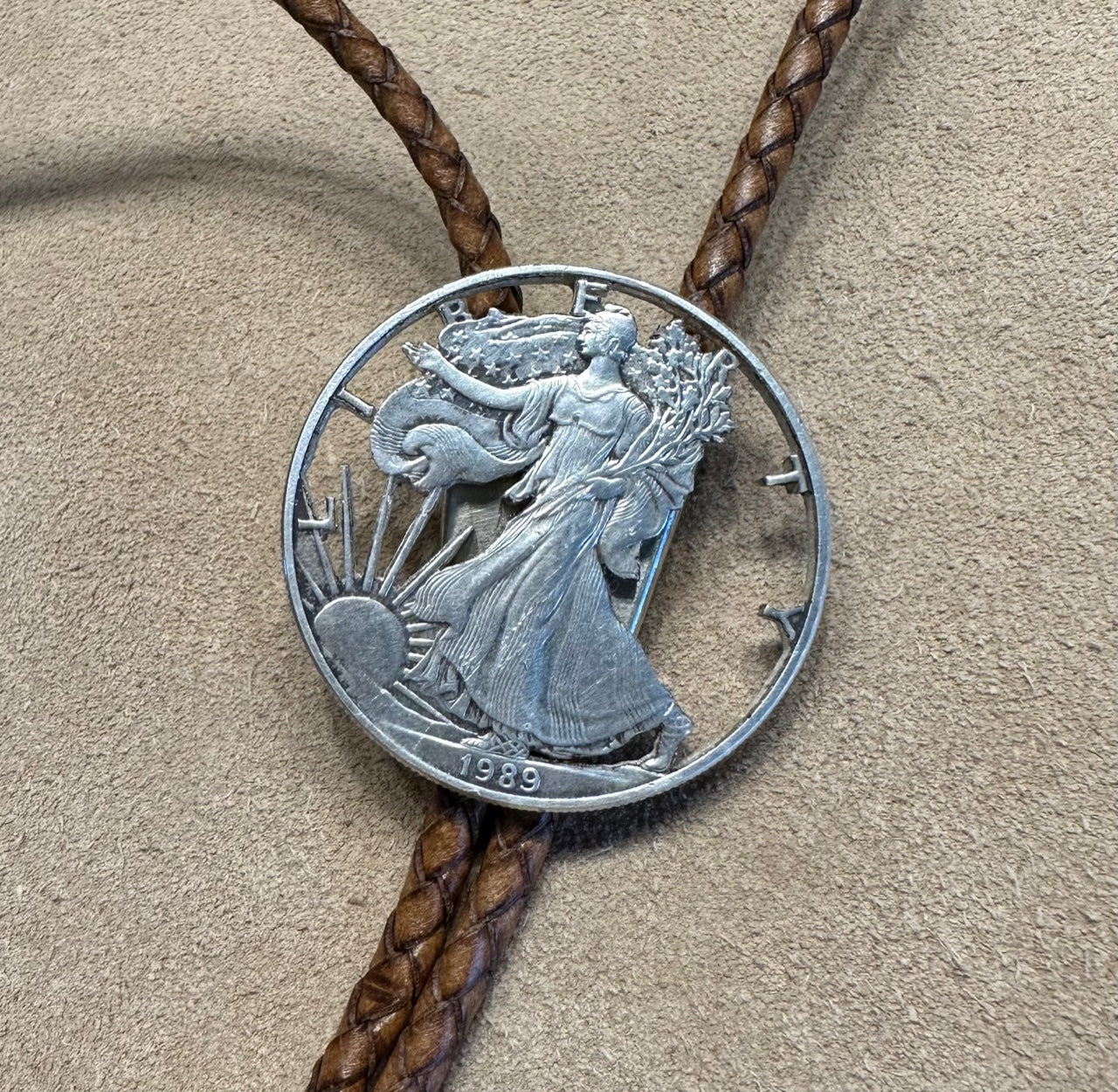 U.S. Silver Eagle Hand Cut Coin Bolo Tie close up on a light cloth background. - Mountainstruck Coin Jewelry
