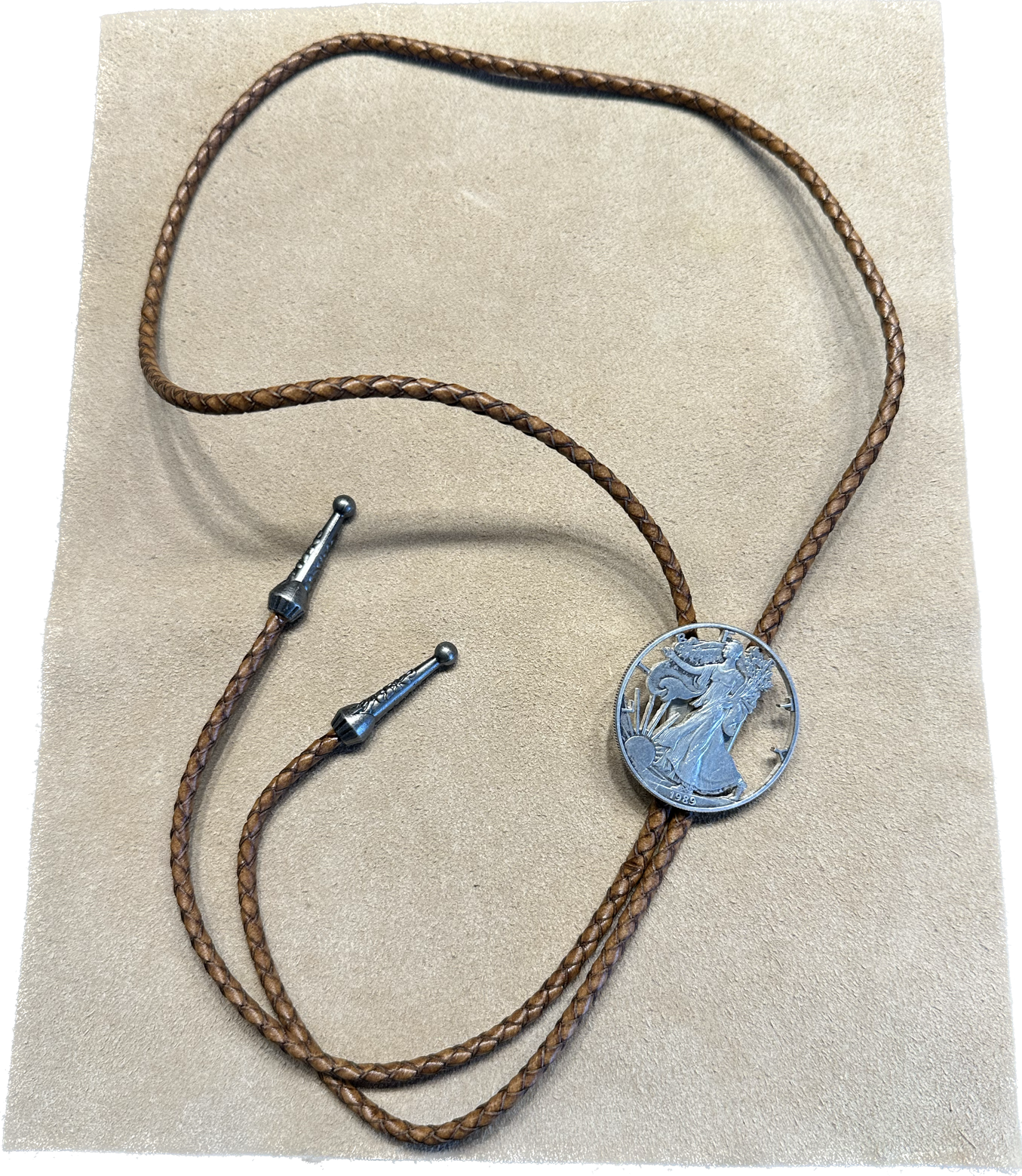 U.S. Silver Eagle Hand Cut Coin Bolo Tie on a light cloth background. - Mountainstruck Coin Jewelry