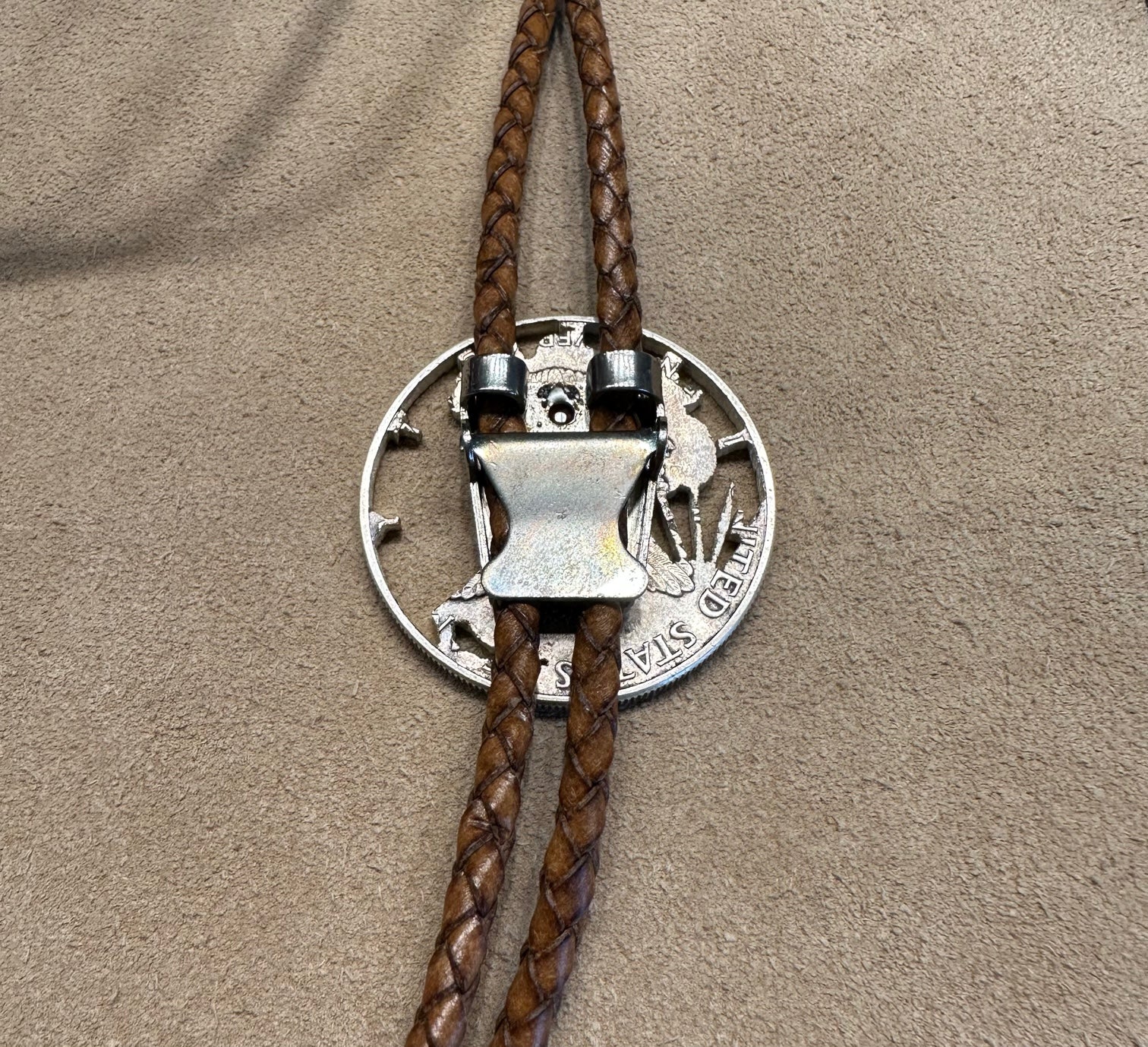 U.S. Silver Eagle Hand Cut Coin Bolo Tie close up on clasp on a light cloth background. - Mountainstruck Coin Jewelry