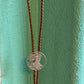 U.S. Silver Eagle Hand Cut Coin Bolo Tie hanging in front of a teal background. - Mountainstruck Coin Jewelry