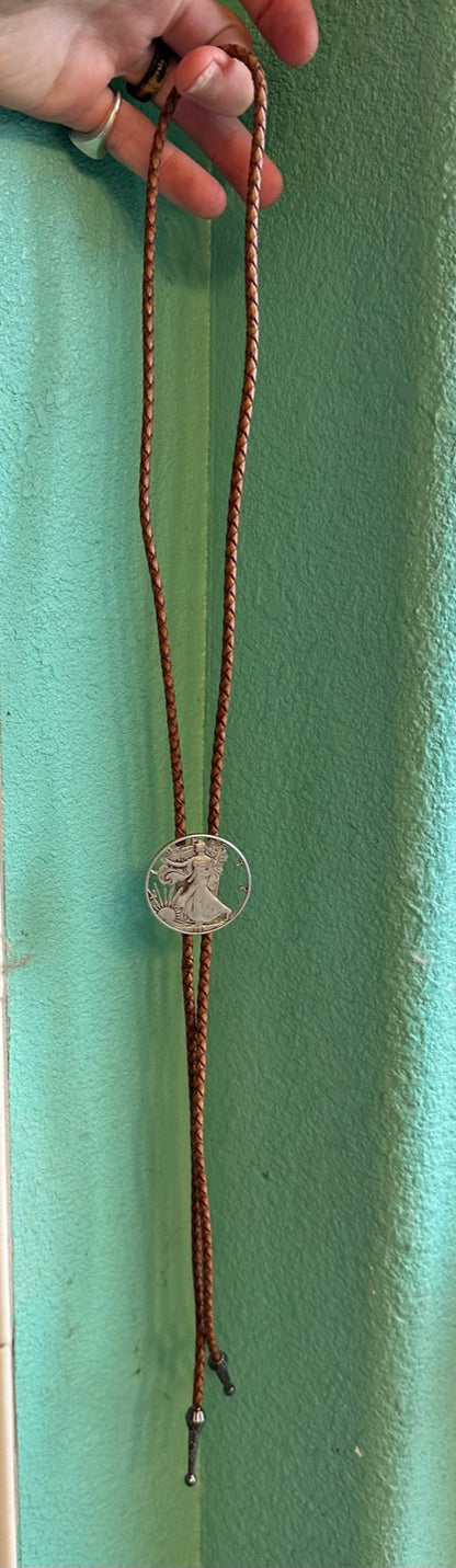 U.S. Silver Eagle Hand Cut Coin Bolo Tie hanging in front of a teal background. - Mountainstruck Coin Jewelry
