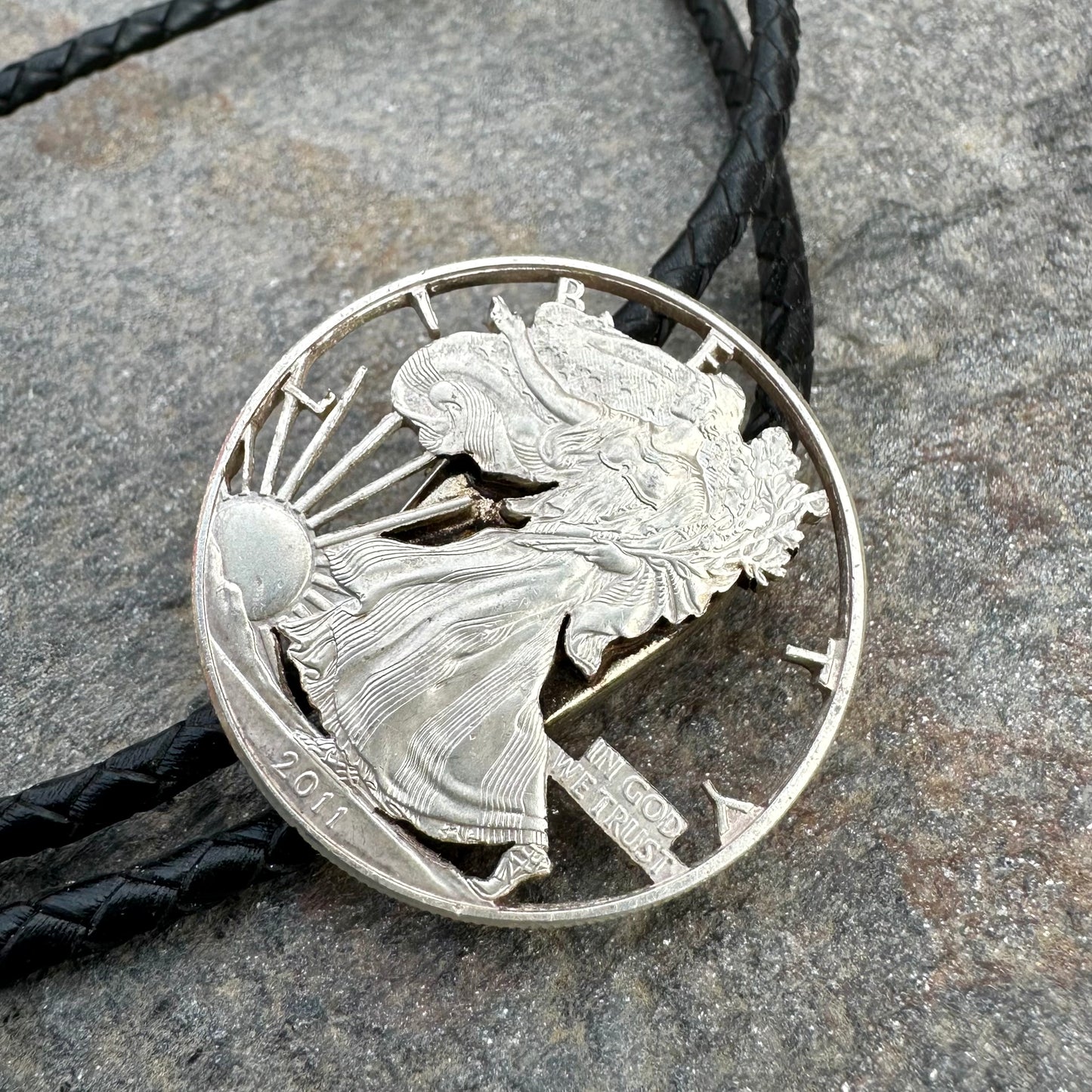 U.S. Silver Eagle Hand Cut Coin Bolo Tie on a grey rock surface. - Mountainstruck Coin Jewelry