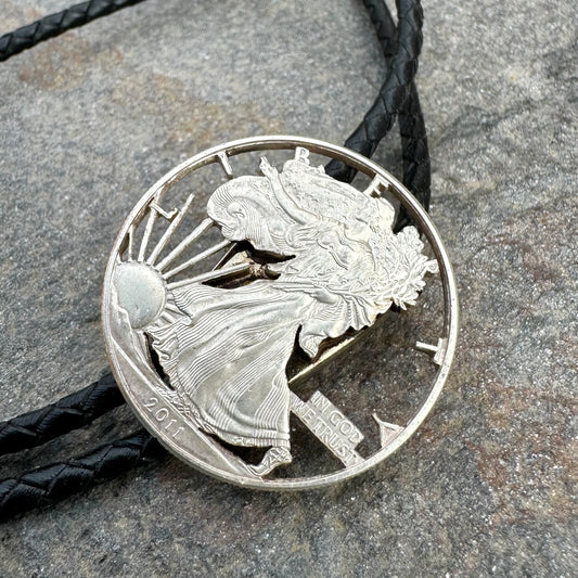 U.S. Silver Eagle Hand Cut Coin Bolo Tie on a grey rock surface. - Mountainstruck Coin Jewelry