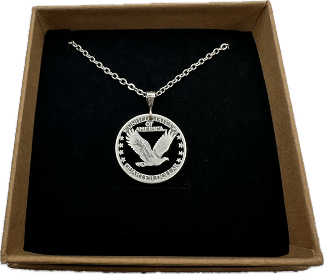 U.S. Soaring Eagle Quarter Hand Cut Silver Coin Necklace on a black velvet background in a brown kraft box. - Mountainstruck Coin Jewelry