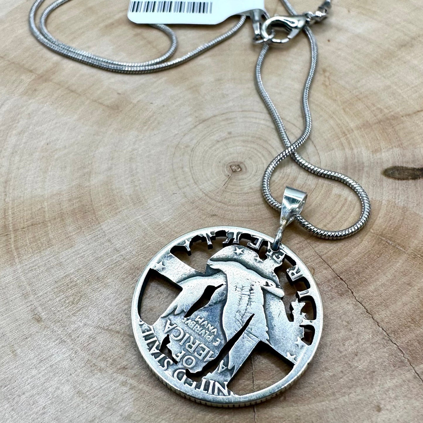 U.S. Standing Liberty Quarter Hand Cut Silver Coin Necklace back on a light wood round. - Mountainstruck Coin Jewelry
