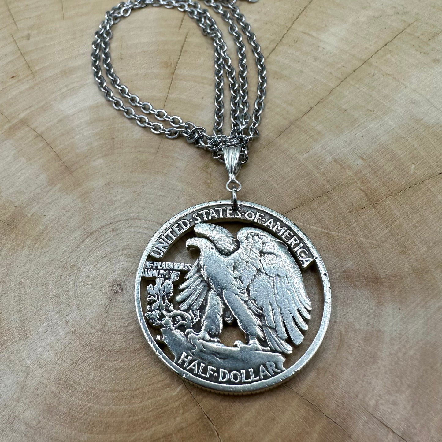 U.S. Walking Liberty Silver Hand Cut Coin Necklace (Eagle) with a snake chain on a light wood background. - Mountainstruck Coin Jewelry