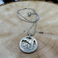 U.S. Yellowstone National Park Quarter Hand Cut Coin Necklace with snake chain on a light wood background. - Mountainstruck Coin Jewelry