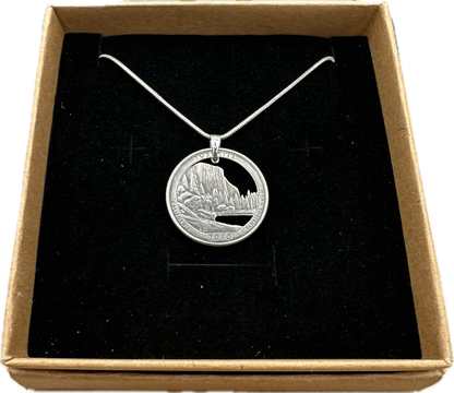 U.S. Yosemite National Park Quarter Hand Cut Coin Necklace with snake chain in a brown kraft box on a black velvet background. - Mountainstruck Coin Jewelry