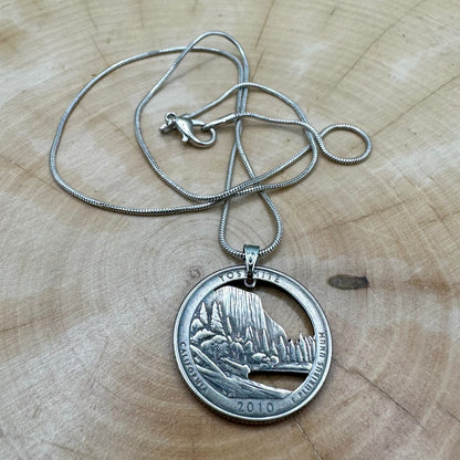 U.S. Yosemite National Park Quarter Hand Cut Coin Necklace with snake chain on a light wood round. - Mountainstruck Coin Jewelry
