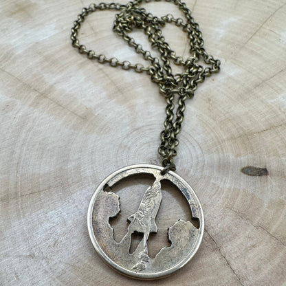 American Innovation $1 Florida Space Shuttle Hand Cut Coin necklace back on a light wood background. - Mountainstruck Coin Jewelry