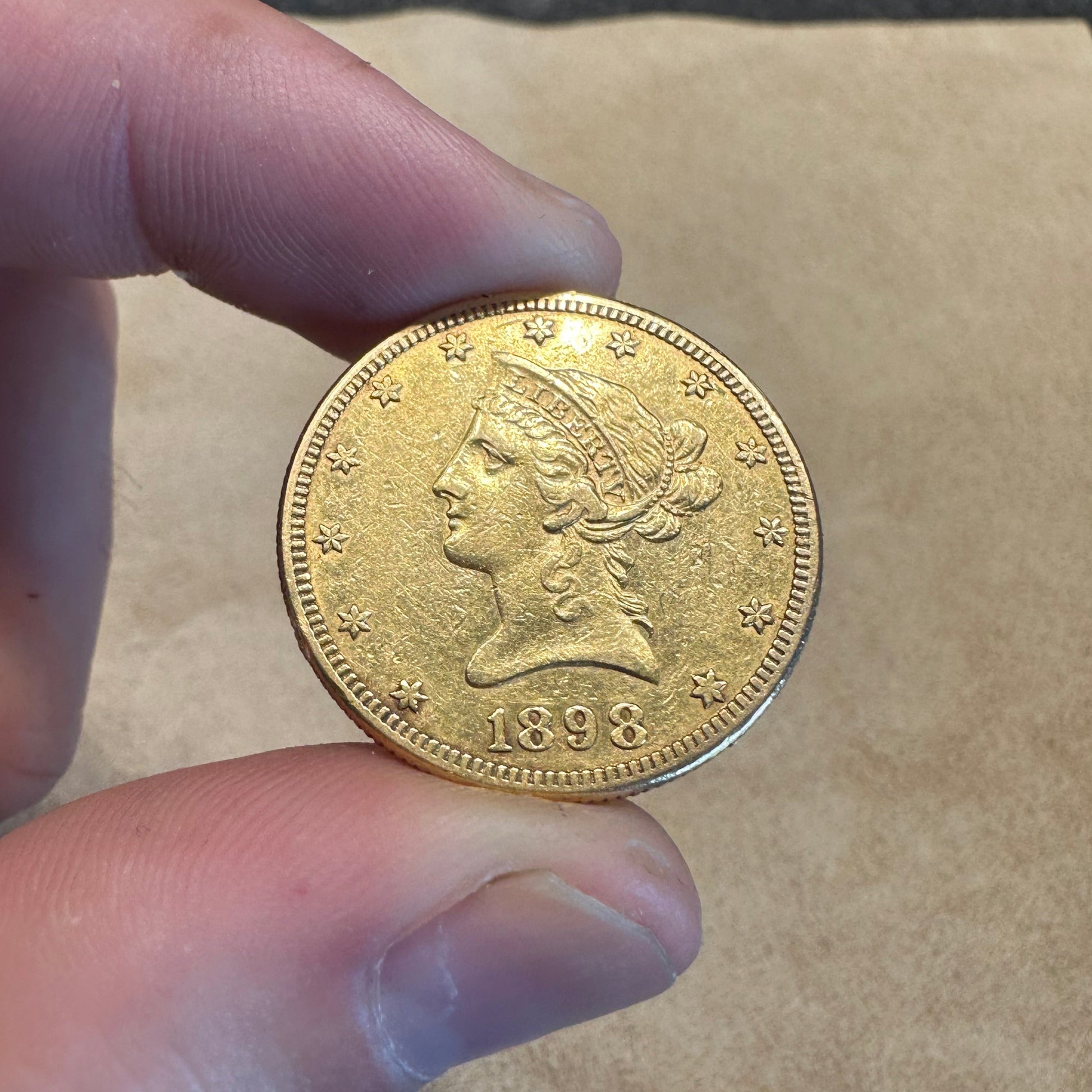 22k U.S. Gold Eagle $10 Coin front held over a light tan cloth. - Mountainstruck Coin Jewelry