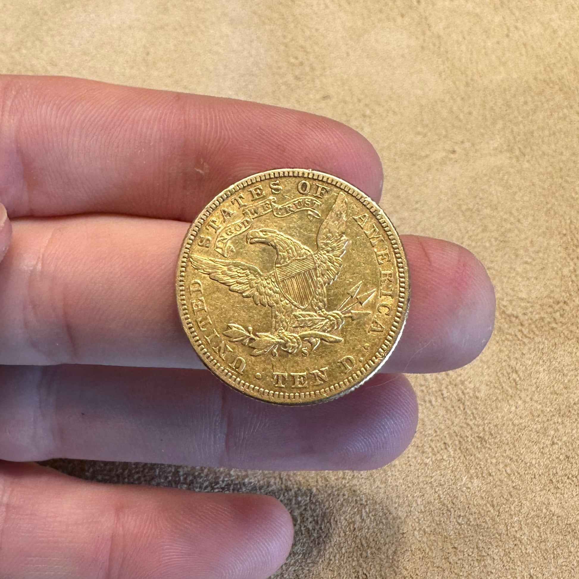 22k U.S. Gold Eagle $10 Coin back held over a light tan cloth. - Mountainstruck Coin Jewelry