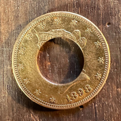 22k U.S. Gold Eagle $10 Coin with hold punched out to make ring on a dark wood table. - Mountainstruck Coin Jewelry