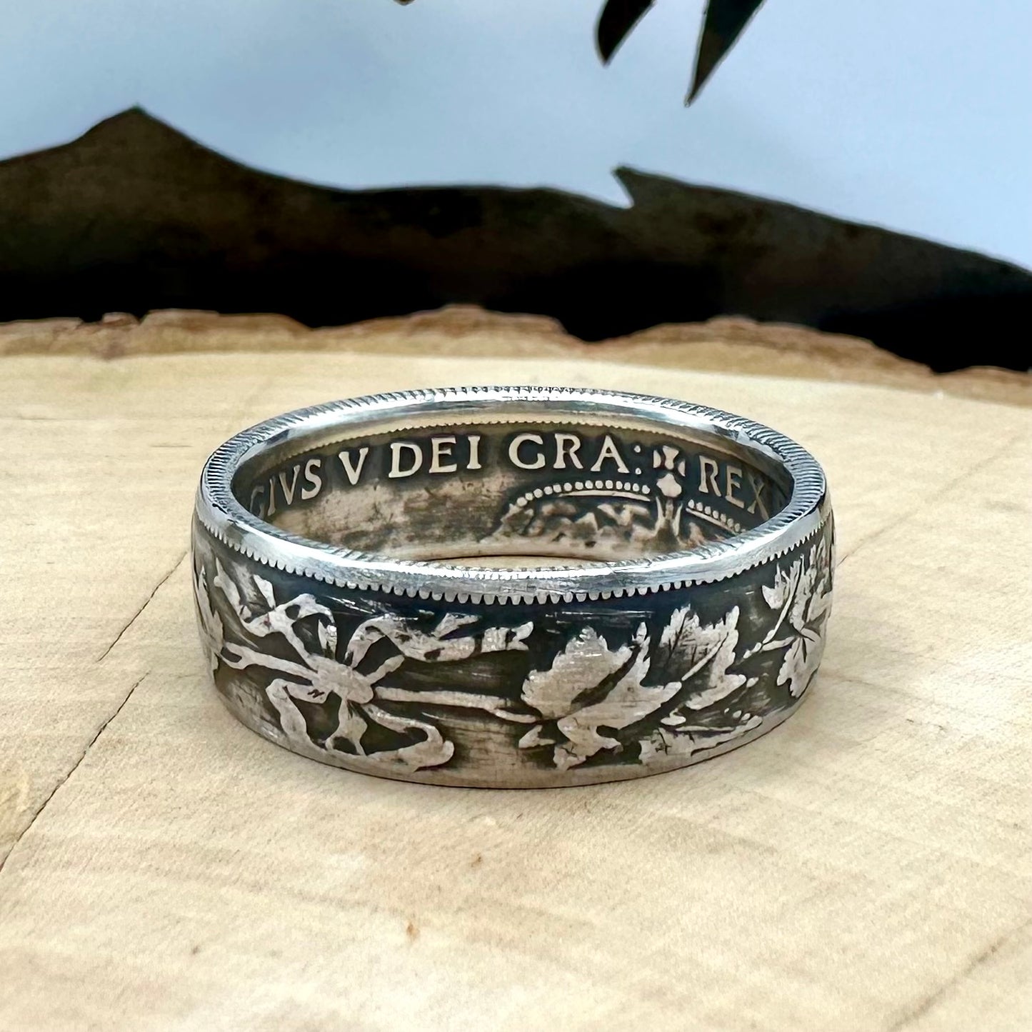 Canada 50 Cents Maple Leaf Silver Ring on a light wood round with a mountain outline background. - Mountainstruck Coin Jewelry