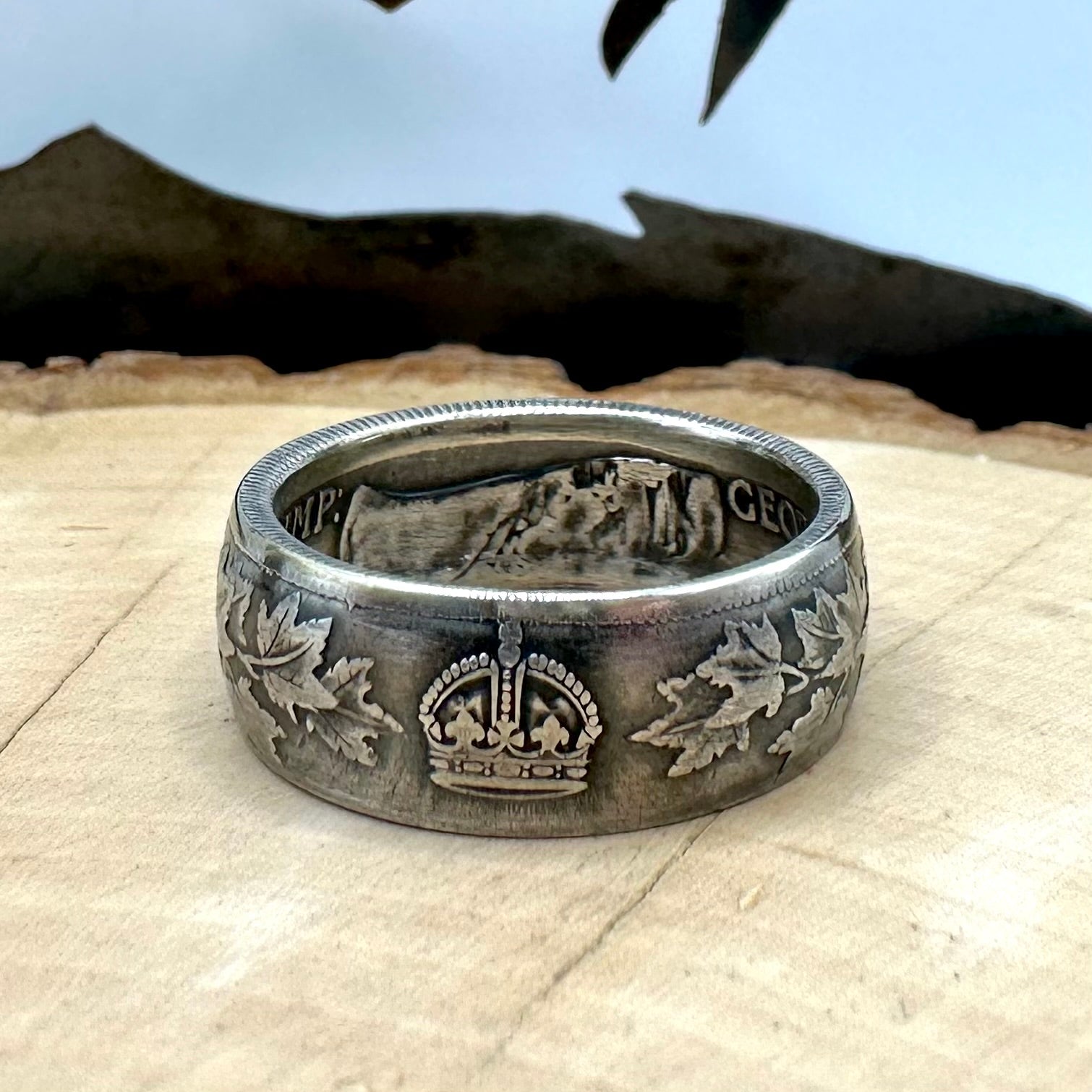 Canada 50 Cents Maple Leaf Silver Ring on a light wood round with a mountain outline background. - Mountainstruck Coin Jewelry