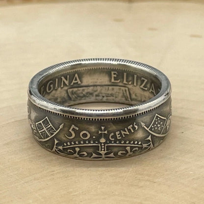 Canada 50 Cents Silver Coin Ring (Lion + Unicorn) on a light wood round with mountain outline in the background. - Mountainstruck Coin Jewelry