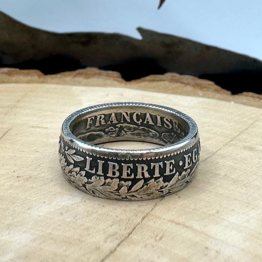 France 2 Franc Silver Coin Ring on a light wood round with a metal mountain background. - Mountainstruck Coin Jewelry