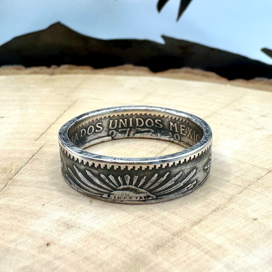 Mexico 50 Centavos Silver Coin Ring (Rare) on a light wood round with mountain outline in the background. 
- Mountainstruck Coin Jewelry