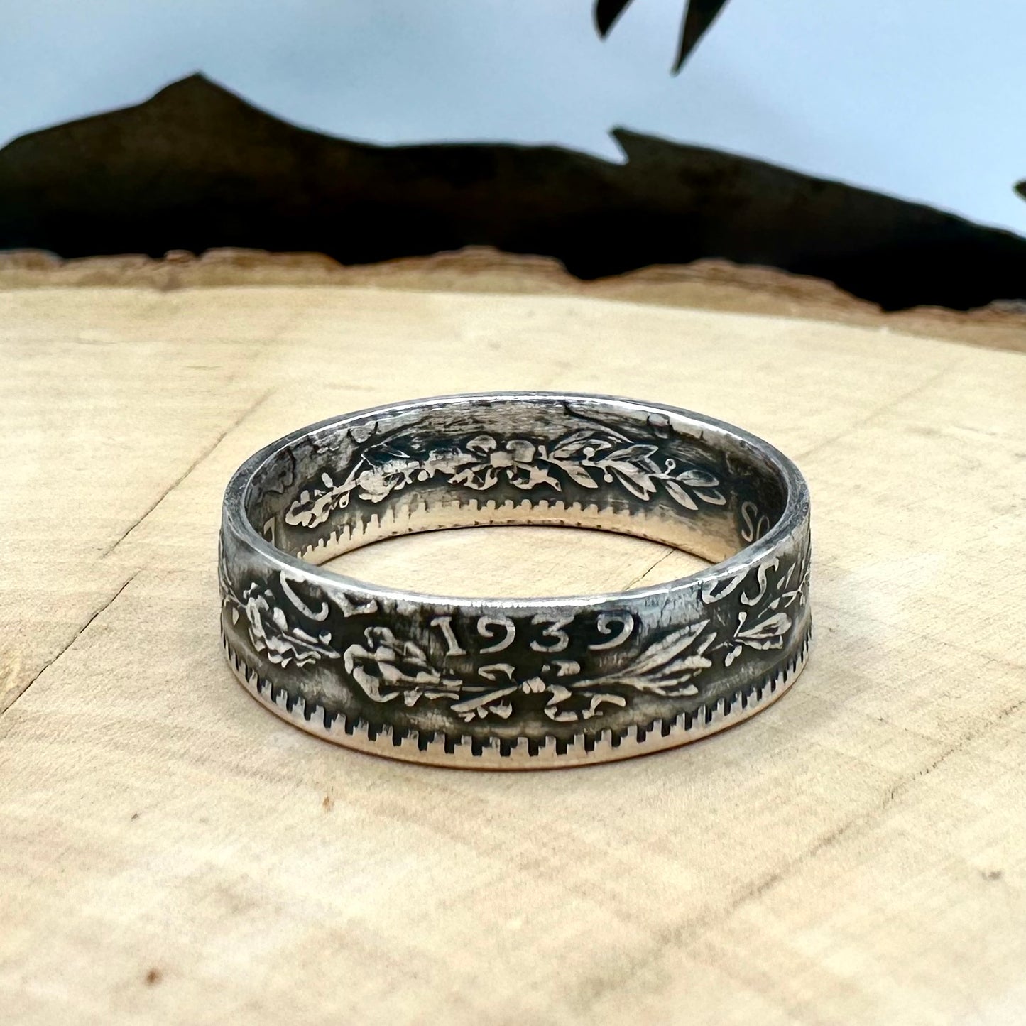 Mexico 50 Centavos Silver Coin Ring (Rare) on a light wood round with mountain outline in the background. - Mountainstruck Coin Jewelry