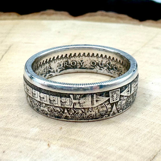 Mexico Aztec Calendar 1/4 oz Silver Round Ring on a light wood round with a metal mountain background. 
- Mountainstruck Coin Jewelry