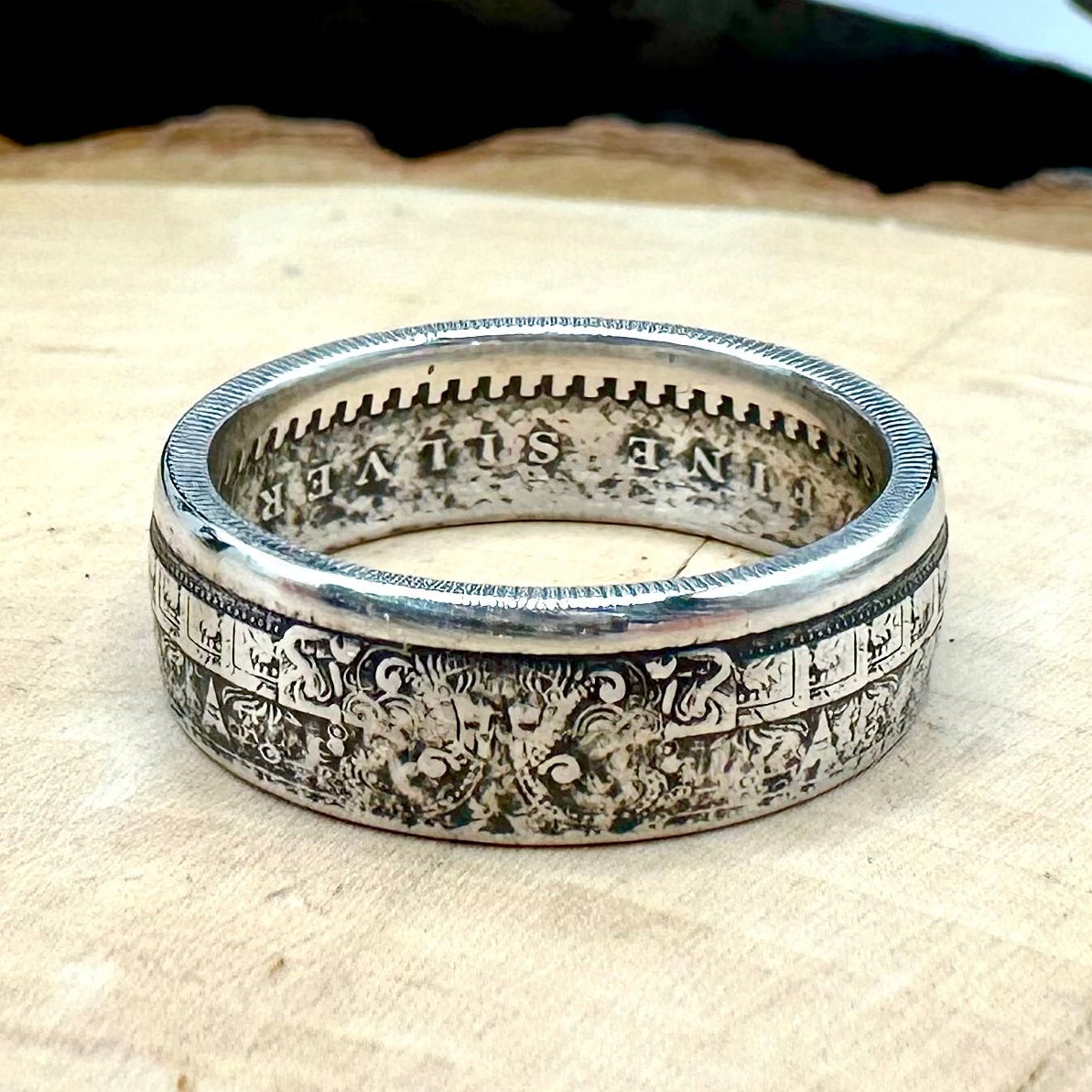 Mexico Aztec Calendar 1/4 oz Silver Round Ring on a light wood round with a metal mountain background. 
- Mountainstruck Coin Jewelry