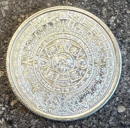 Mexico Aztec Calendar 1/4 oz Silver Round (back) on a dark concrete background. 
- Mountainstruck Coin Jewelry